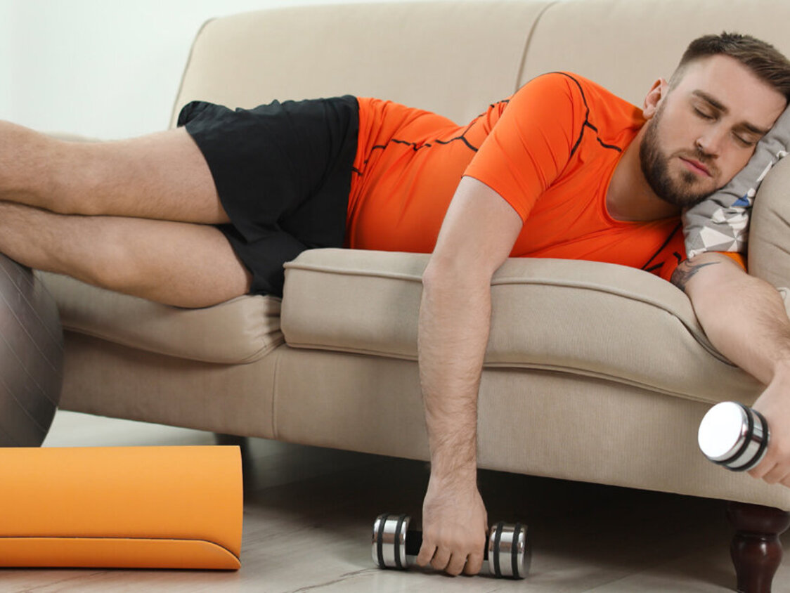Lazy,Young,Man,With,Sport,Equipment,On,Sofa,At,Home