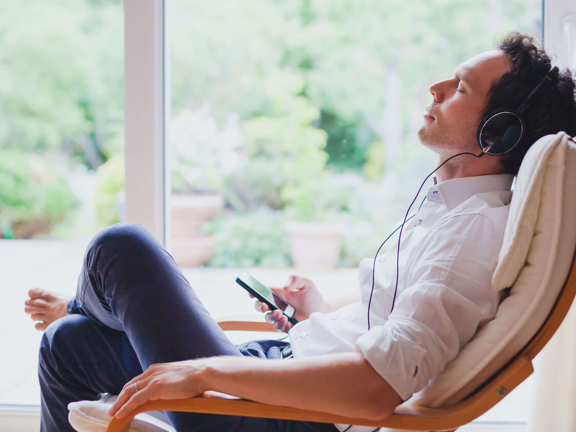Listen relaxing music at home, relaxed man sitting in headphones.