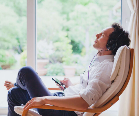 Listen relaxing music at home, relaxed man sitting in headphones.