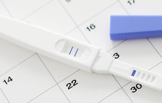  Ein Schwangerschaftstest mit zwei Streifen auf einem Kalender.